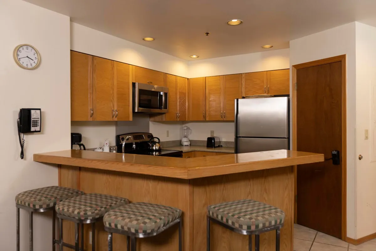 A functional and inviting kitchen with a prominent counter, stools for casual seating, modern appliances including a microwave and refrigerator, and well-organized cabinetry. The layout encourages participation in meal preparation and easy socializing with family or guests.