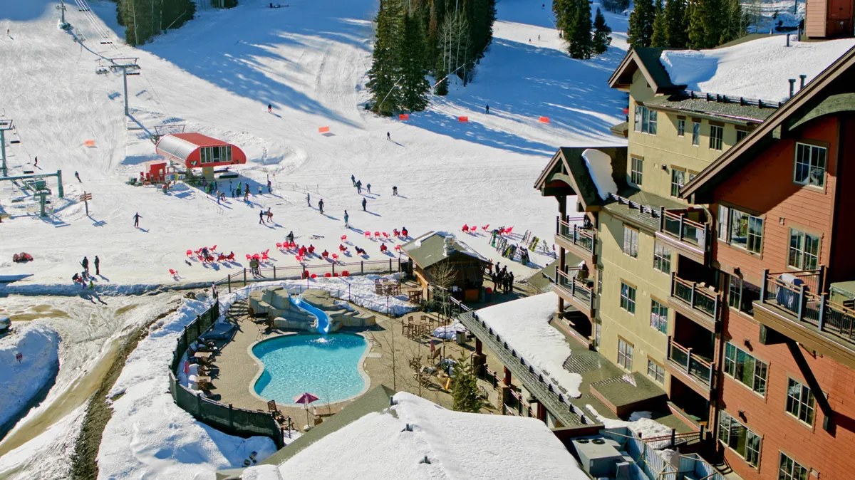 A dynamic exterior scene featuring the resort's ski slopes with active skiers, ski lifts in motion, a snow-blanketed lodge, and a heated outdoor swimming pool nestled near the action. The area buzzes with energy, blending the thrill of winter sports with the relaxing atmosphere of the pool and après-ski gatherings.